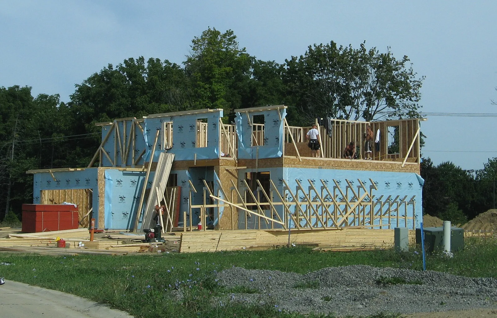Two-storey house under construction with exposed timber walls.