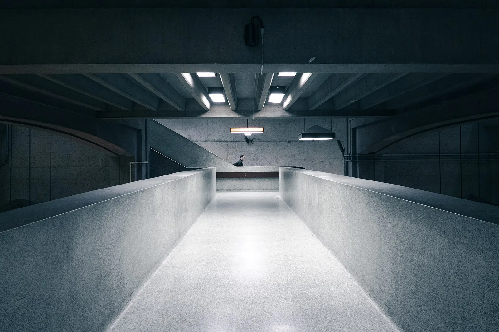 Concrete interior walkway with a low parapet and linear lights.